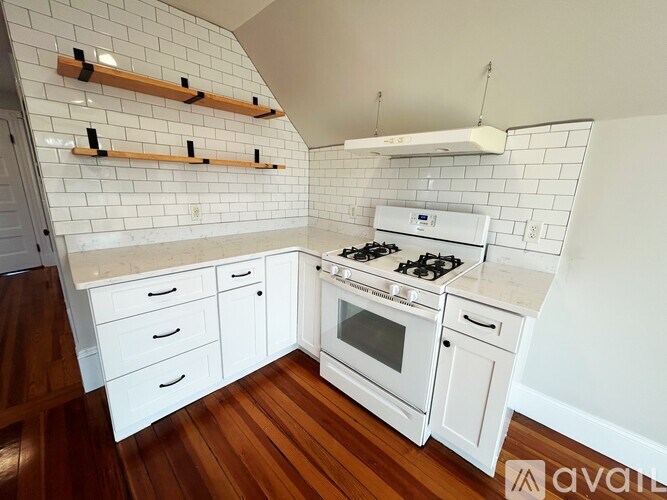 A kitchen with white cabinets and a white stove top oven.