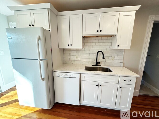 A kitchen with white cabinets and a white fridge.