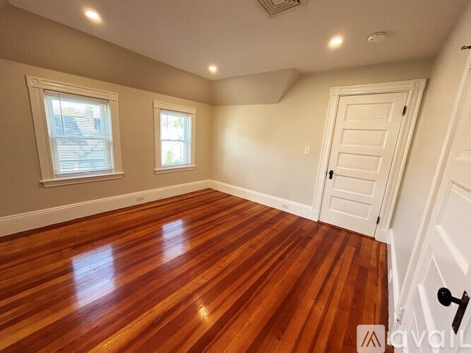 A room with wooden flooring and white walls.