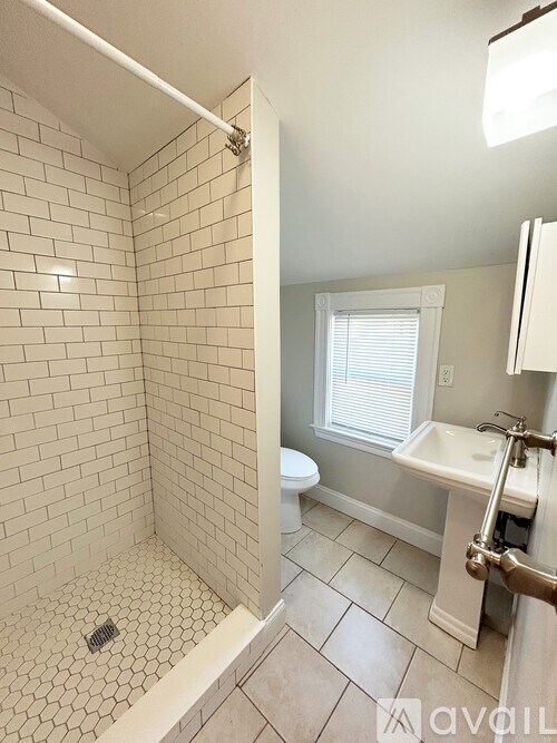 A bathroom with a white tiled shower and a white sink.
