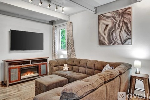 A living room with a brown couch, a fireplace, and a painting on the wall.