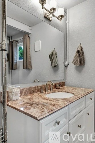 A bathroom with a marble countertop and white cabinets.