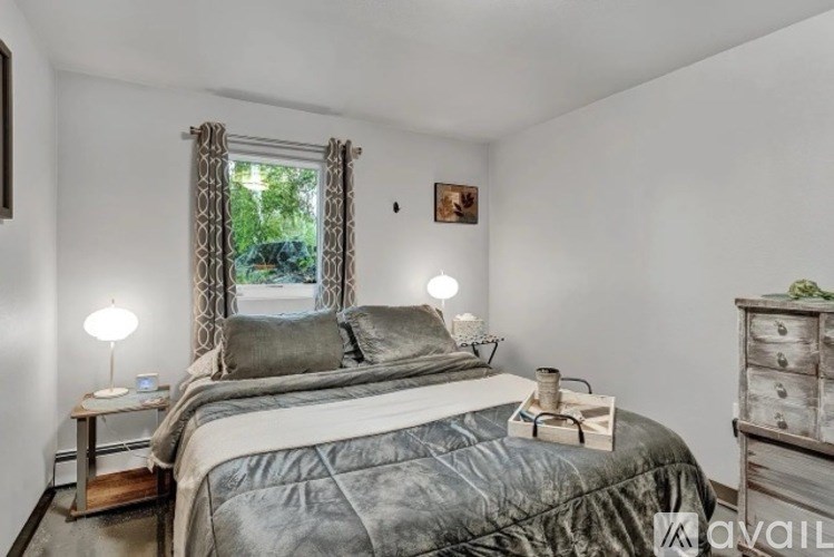 A bedroom with a large bed and a window with curtains.