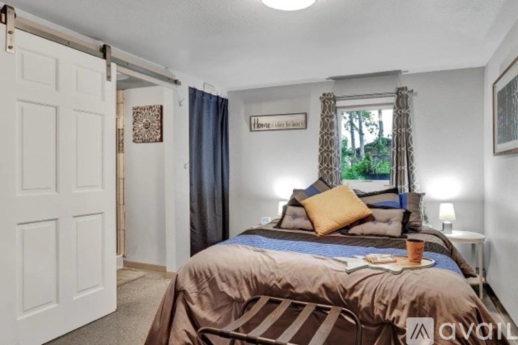 A bedroom with a bed, nightstand, and a window with curtains.