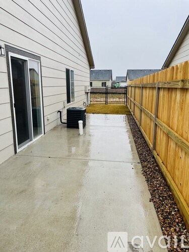 A concrete patio leads to a wooden fence.