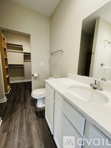 A bathroom with a toilet, sink, and mirror.