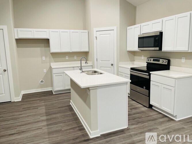 A kitchen with white cabinets and a wooden floor.