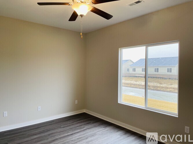 A room with a ceiling fan and a large window.