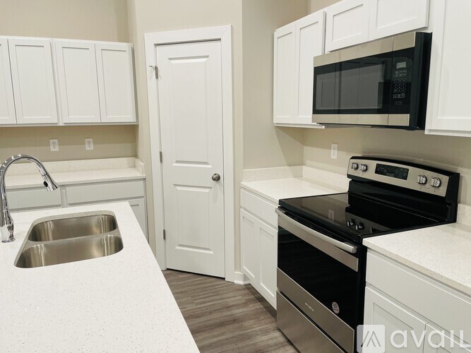 A kitchen with white cabinets and a black microwave.