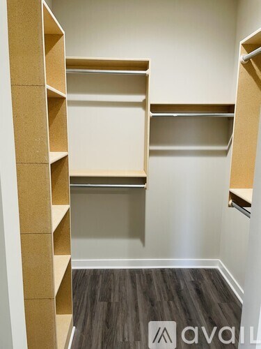 A room with a wall of shelves and a wooden floor.