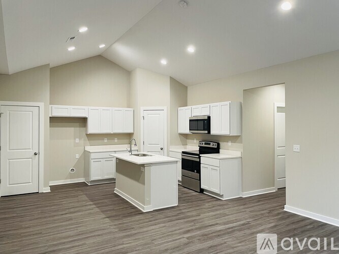 A well-lit, spacious kitchen with white cabinets and a wooden floor.