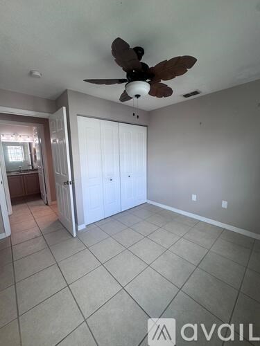 A room with a ceiling fan and tile flooring.