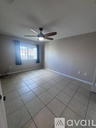 A room with a ceiling fan and tile flooring.