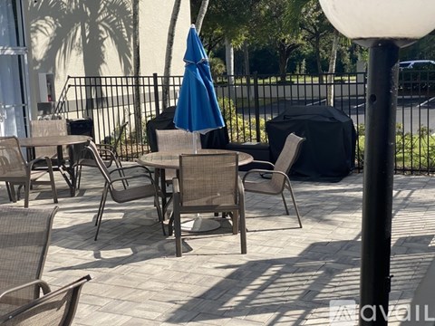 A patio with chairs and a table with a blue umbrella.