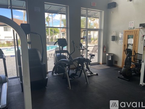 A gym with treadmills, exercise bikes, and a view of the pool outside.