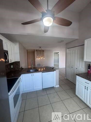A kitchen with white cabinets and a ceiling fan.