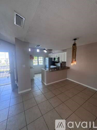 A room with a tiled floor and a counter with a microwave on it.