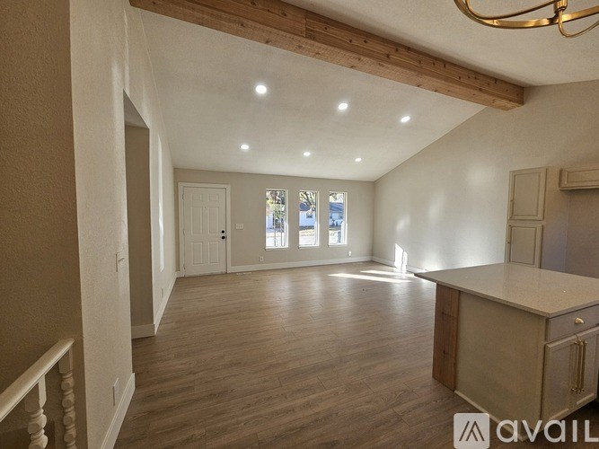 A spacious room with wooden floors and a large window.