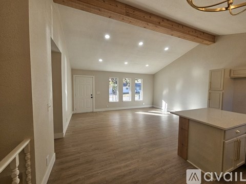 A spacious room with wooden floors and a large window.
