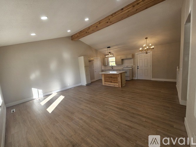 A spacious room with wooden flooring and a chandelier hanging from the ceiling.