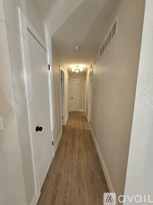 A long hallway with wood floors and white walls.