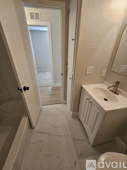 A bathroom with a sink, mirror, and a door leading to another room.