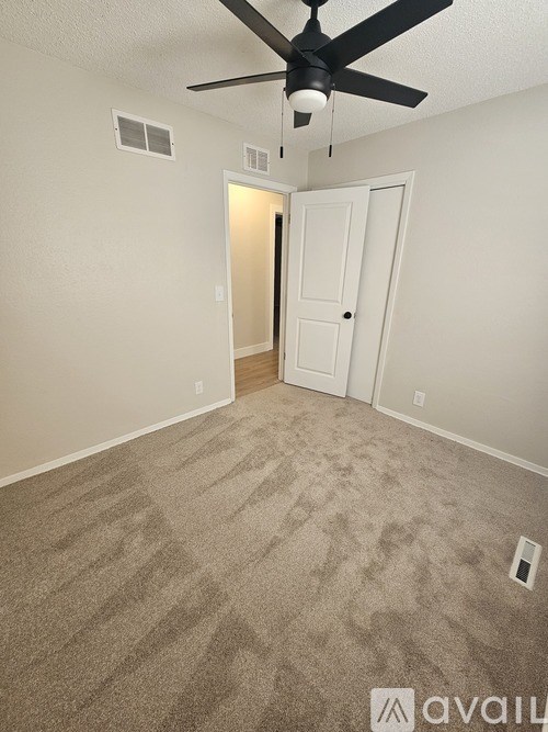 A room with a ceiling fan and carpeted floor.