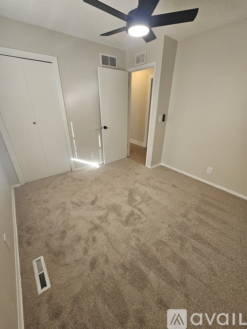 A room with a carpeted floor and a ceiling fan.
