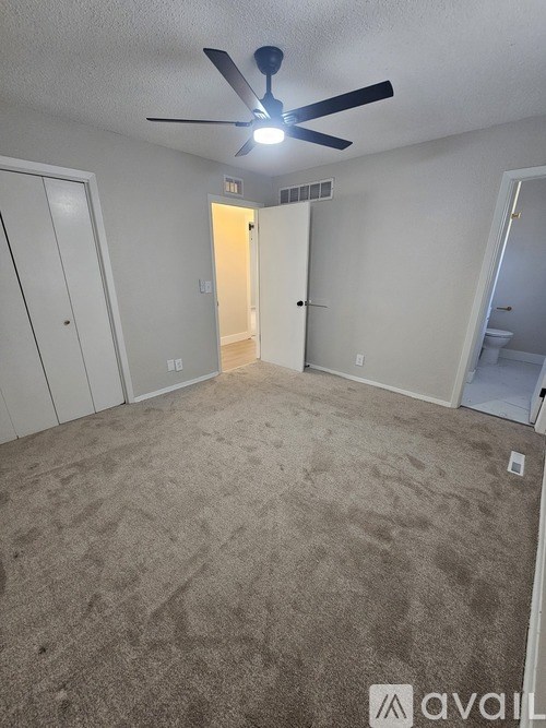 A room with a ceiling fan and carpeted floor.