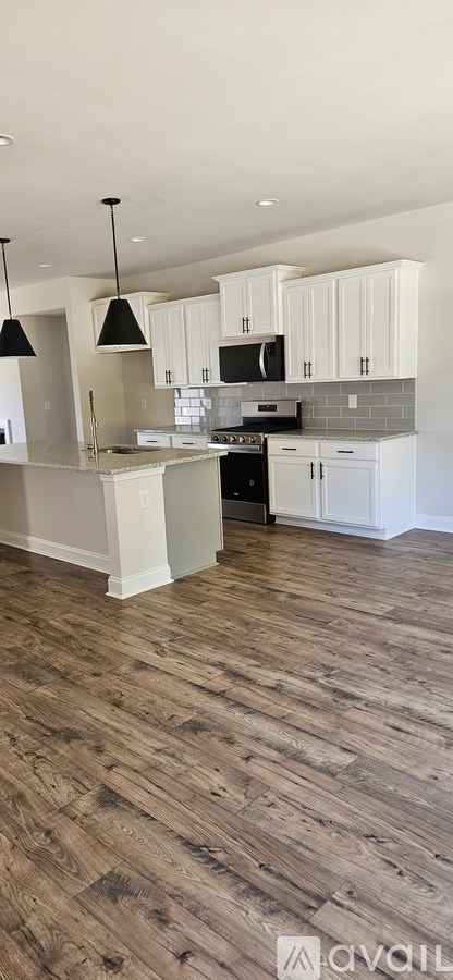 A kitchen with white cabinets and a wooden floor.