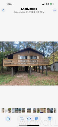 A wooden house with a balcony is surrounded by trees.
