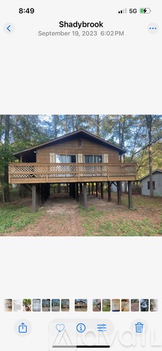 A wooden house with a balcony is surrounded by trees.