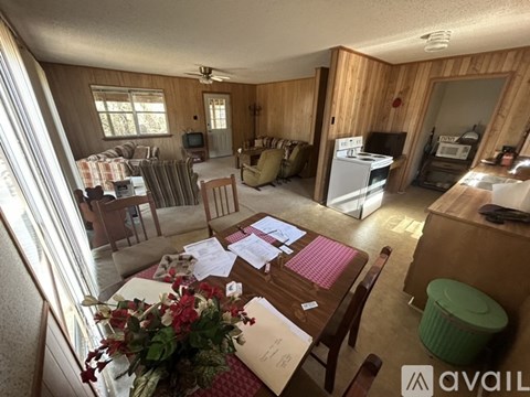 A living room with a couch, chairs, and a dining table with papers on it.