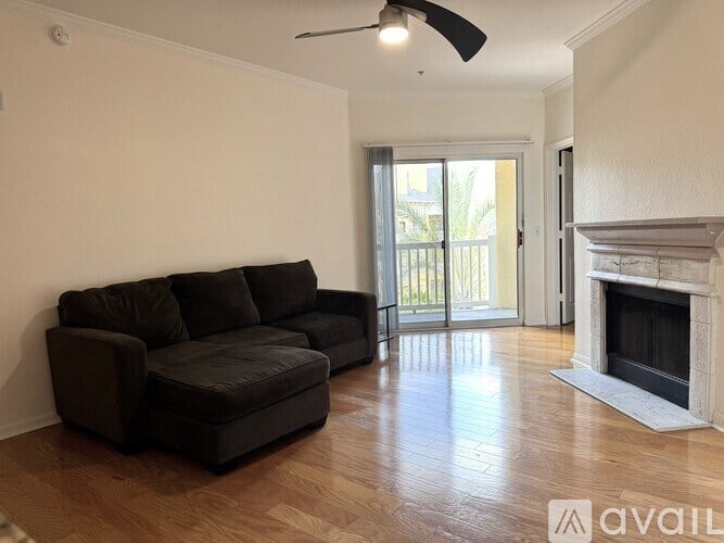 A black sofa in a room with a fireplace and sliding glass doors.