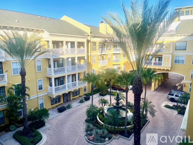 A sunny day at a yellow apartment complex with palm trees and a fountain.