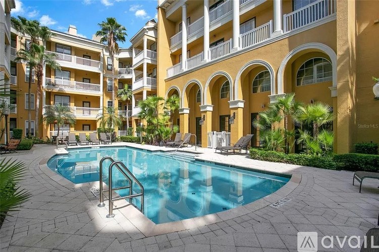 A swimming pool is surrounded by a stone patio and palm trees.