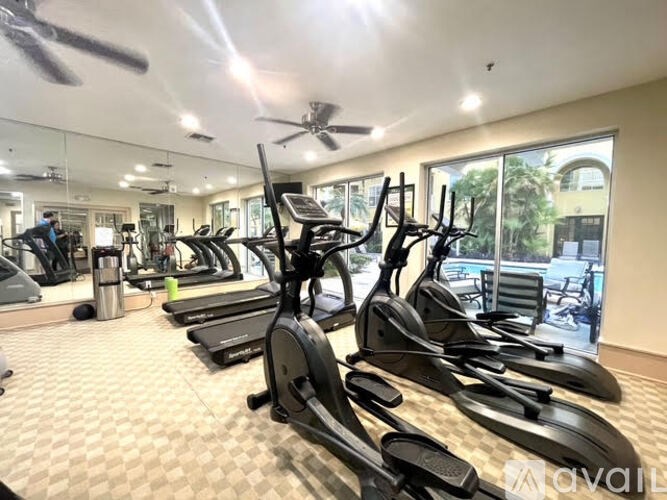 A gym with treadmills, elliptical machines, and a fan.