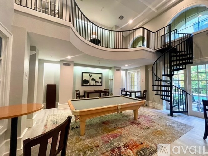 A living room with a pool table and a spiral staircase.