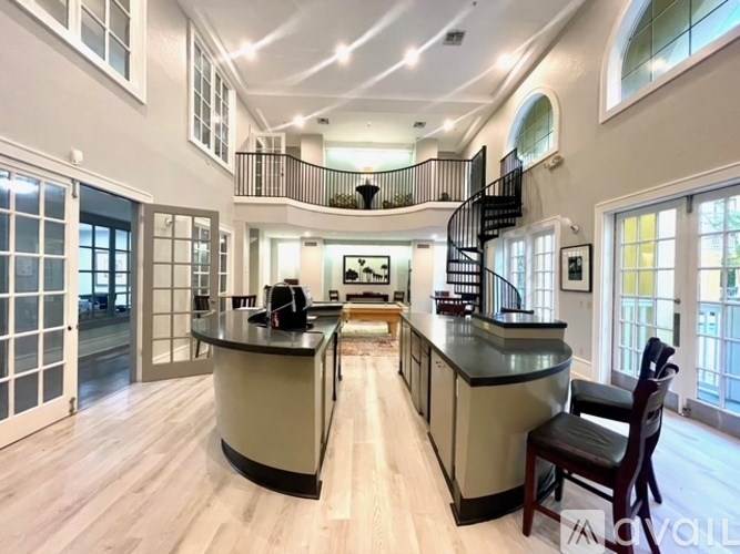 A spacious kitchen with a curved island and a staircase in the background.