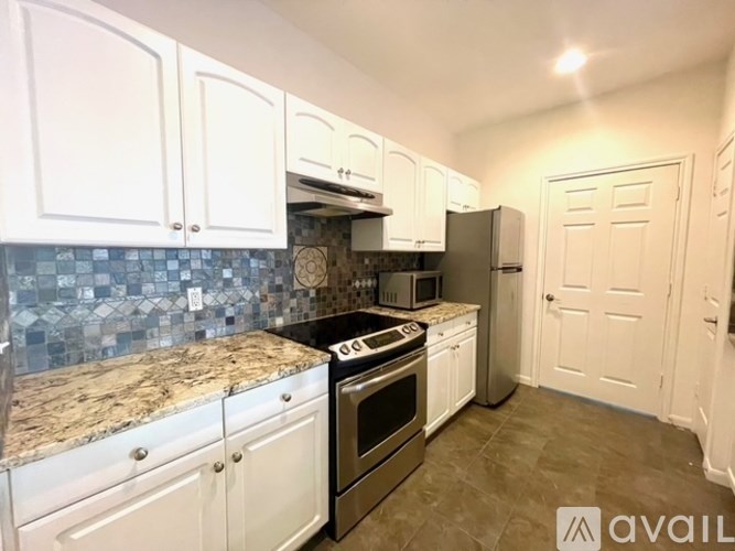 A kitchen with white cabinets and a granite countertop.