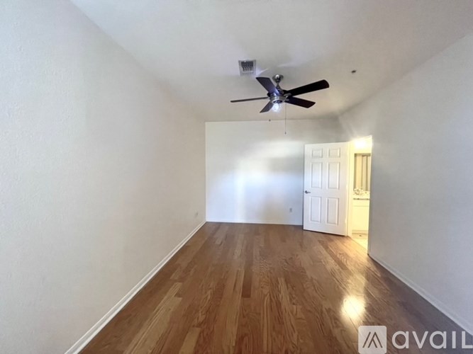A room with a ceiling fan and wooden flooring.