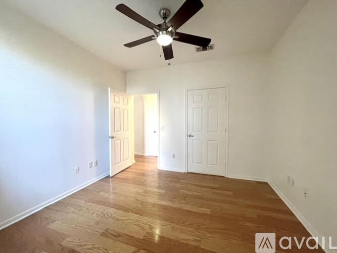 A room with a ceiling fan and wooden flooring.