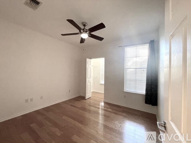 A room with a ceiling fan and wooden flooring.