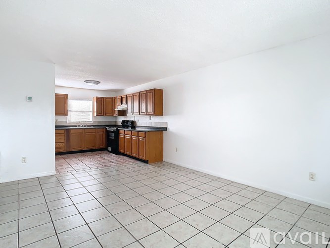 A kitchen with white walls and brown cabinets.