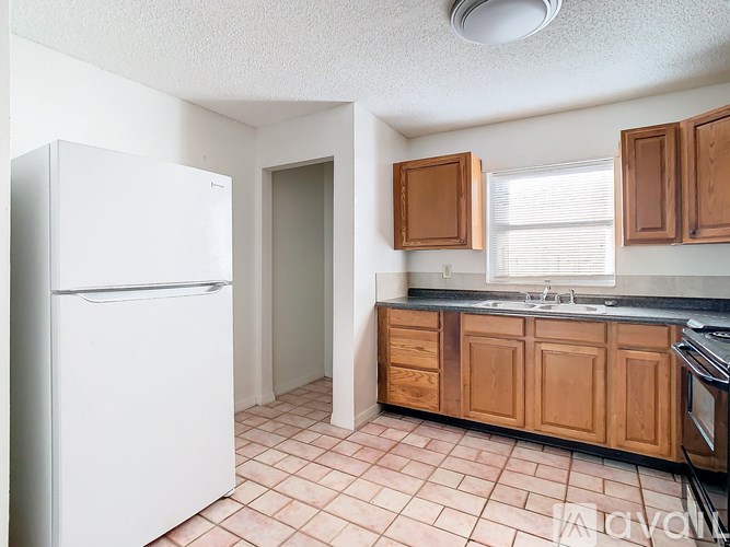 A kitchen with a white refrigerator and wooden cabinets.