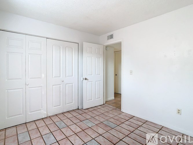 A room with white doors and a tiled floor.