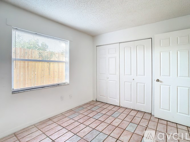 A room with a tiled floor and a window with blinds.