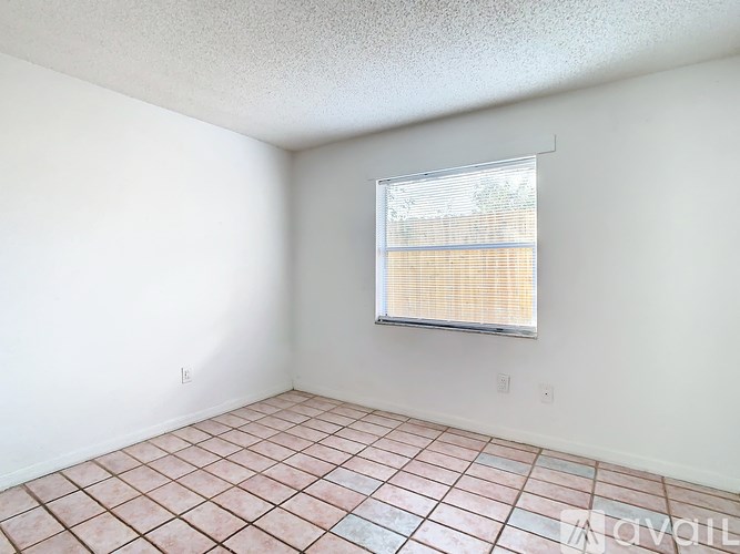 A room with a window covered by a screen and tiled flooring.