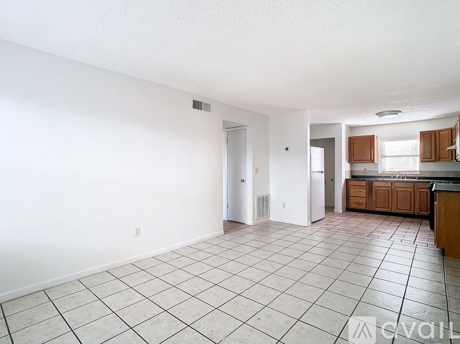 A spacious living room with white walls and a tiled floor.
