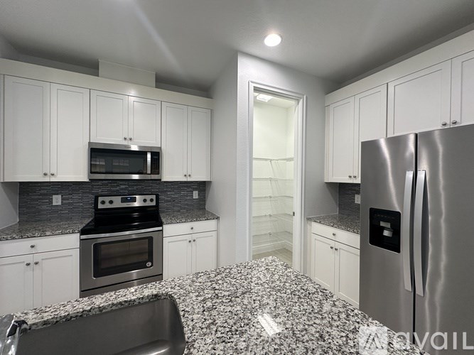 A kitchen with white cabinets and a granite countertop.